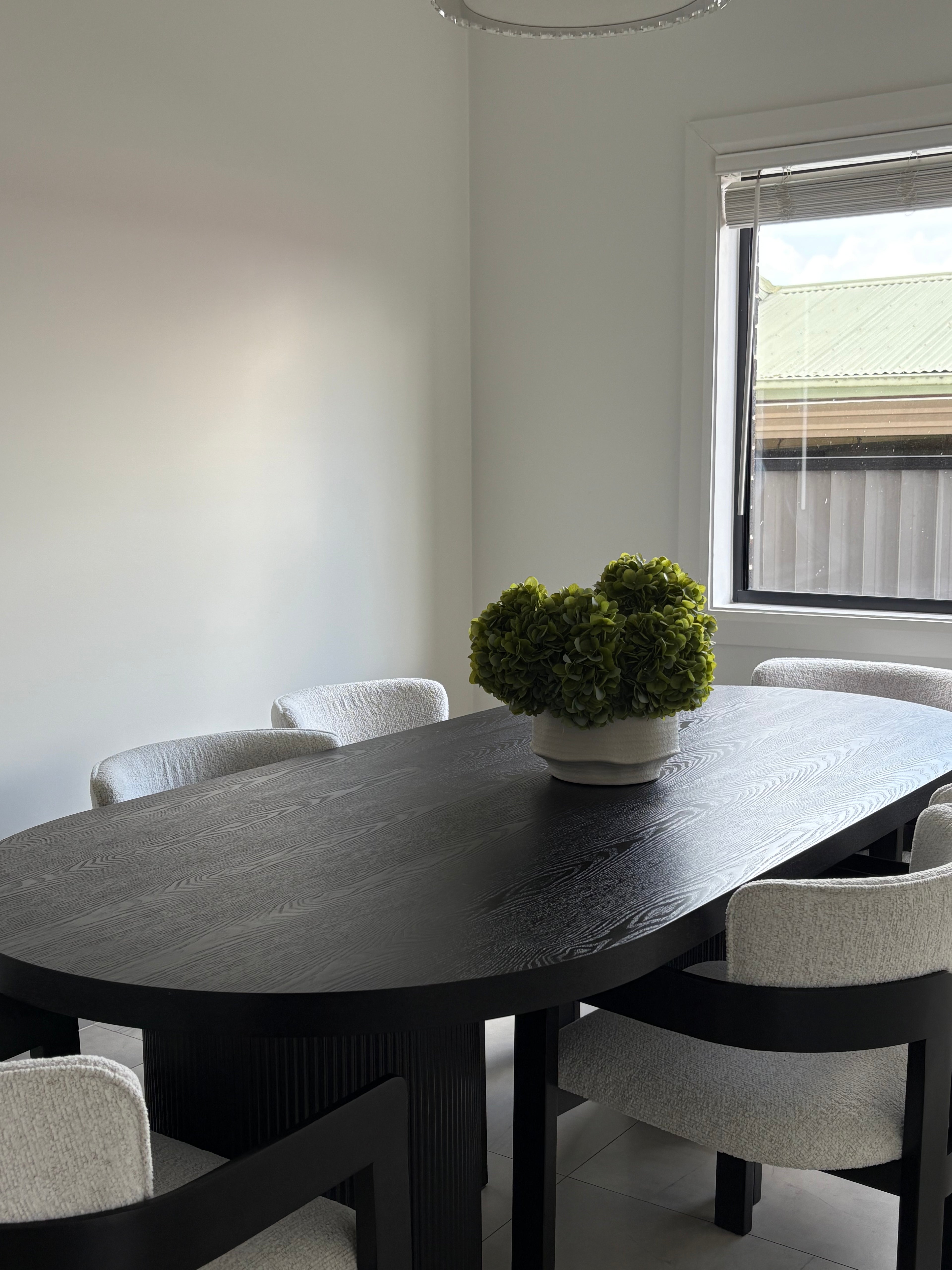 Artificial green hydrangea arrangement in white pot on black table
