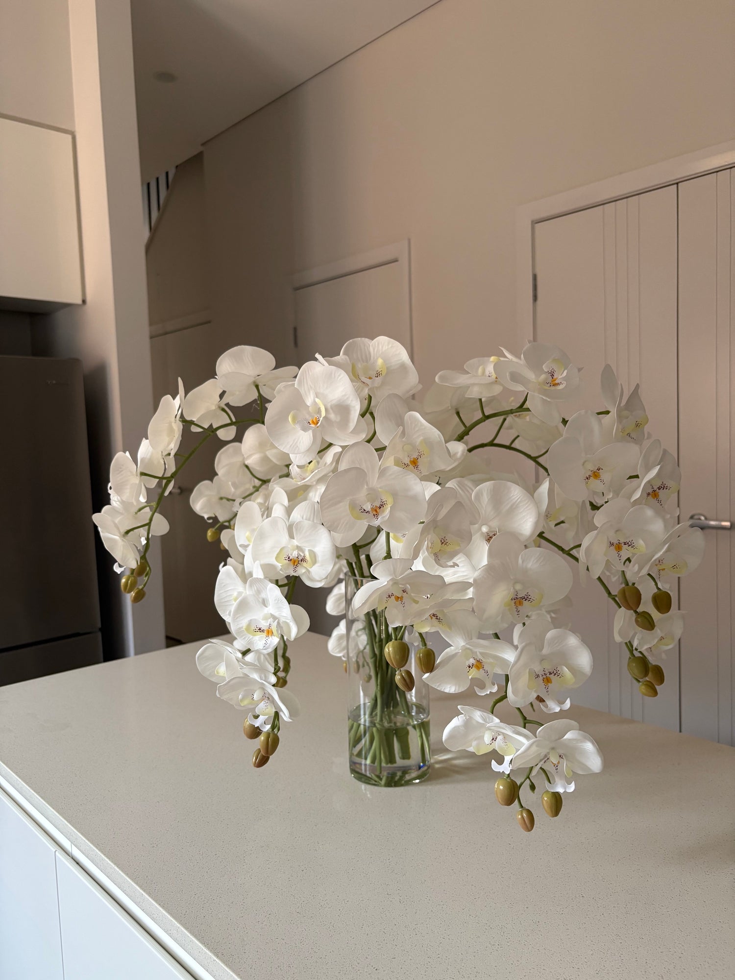 Artificial orchid arrangements and faux orchid stems styled in vase