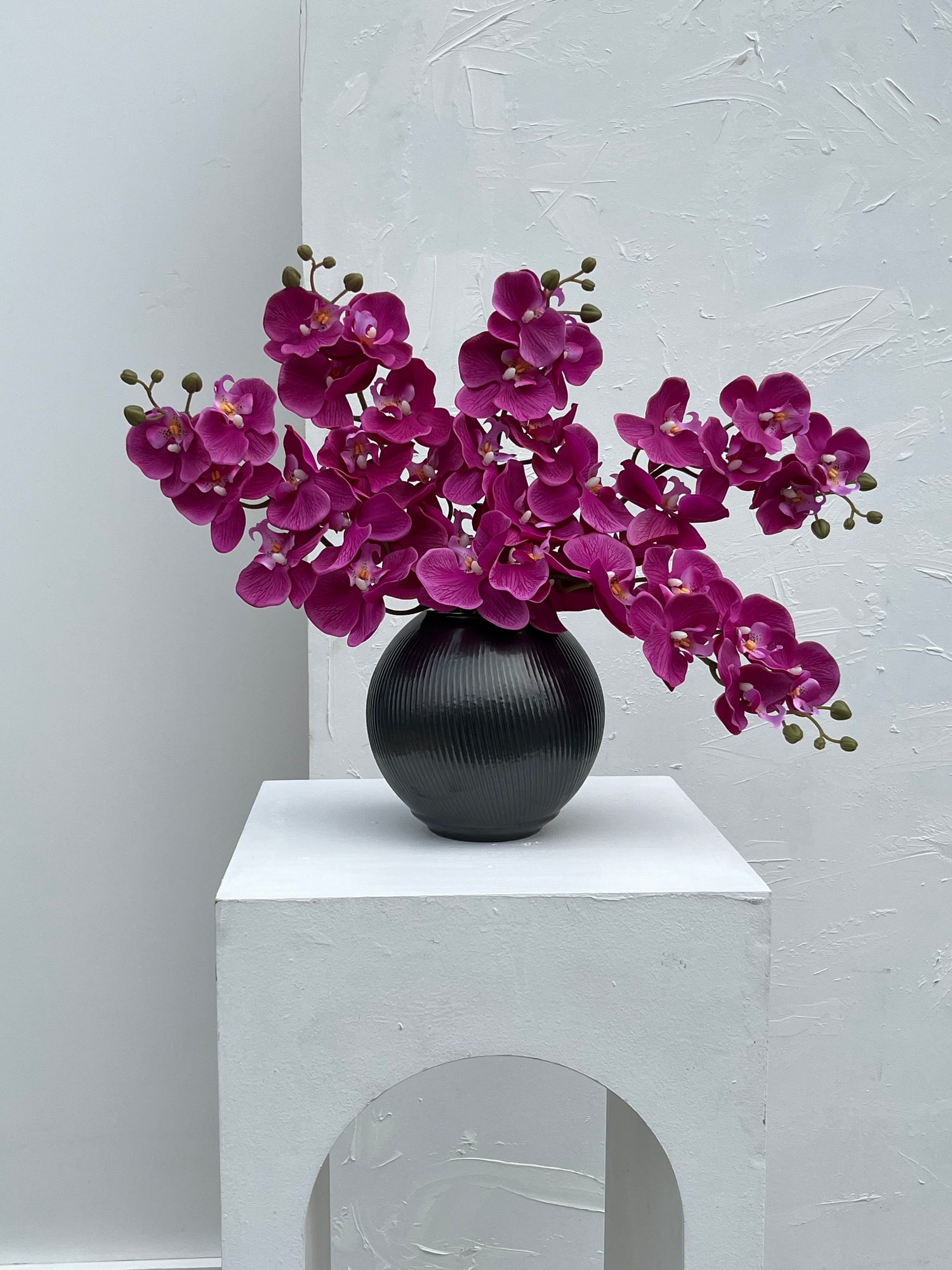 Orchid arrangement in black vase