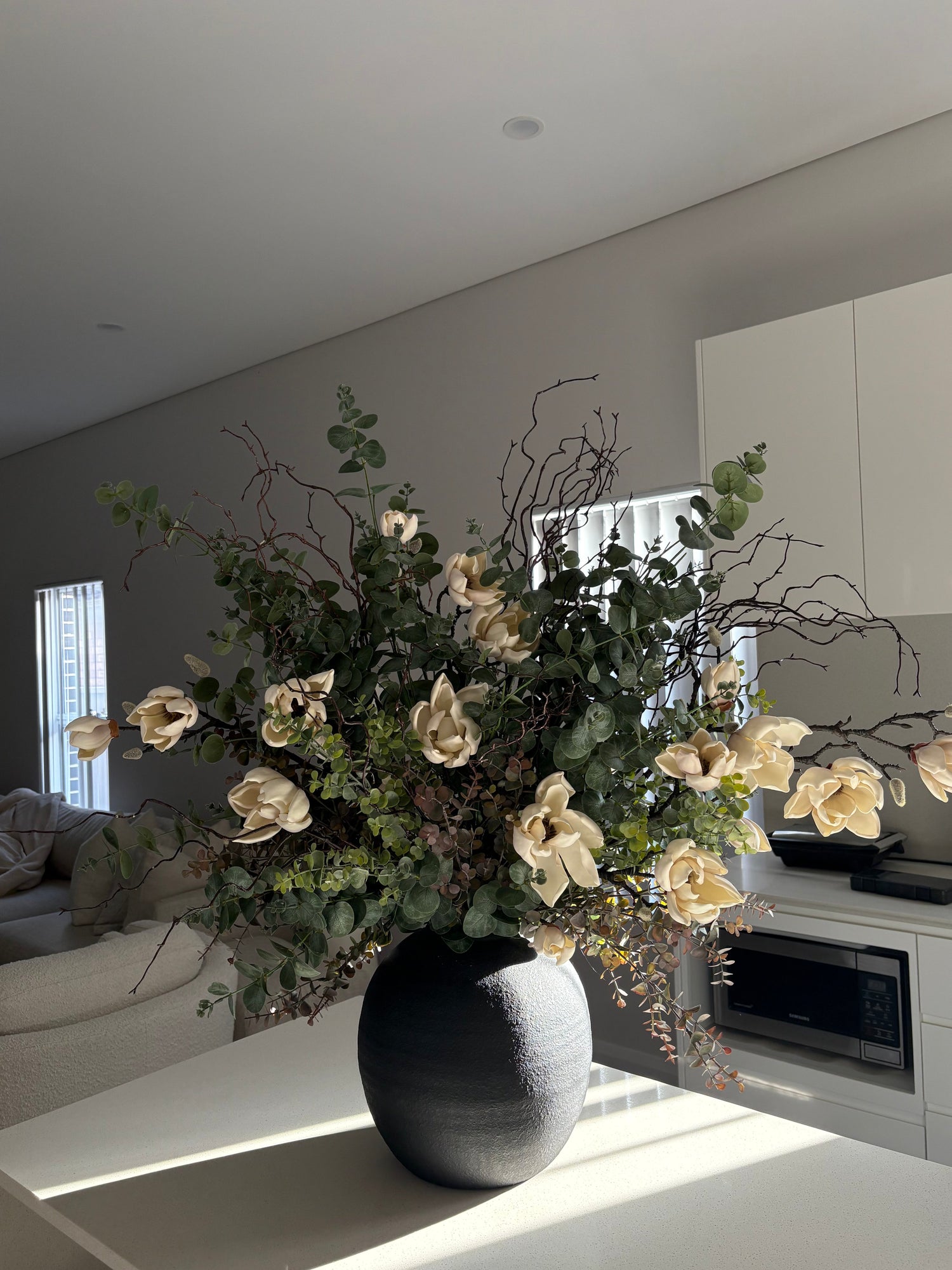 Large artificial magnolia arrangement in black vase