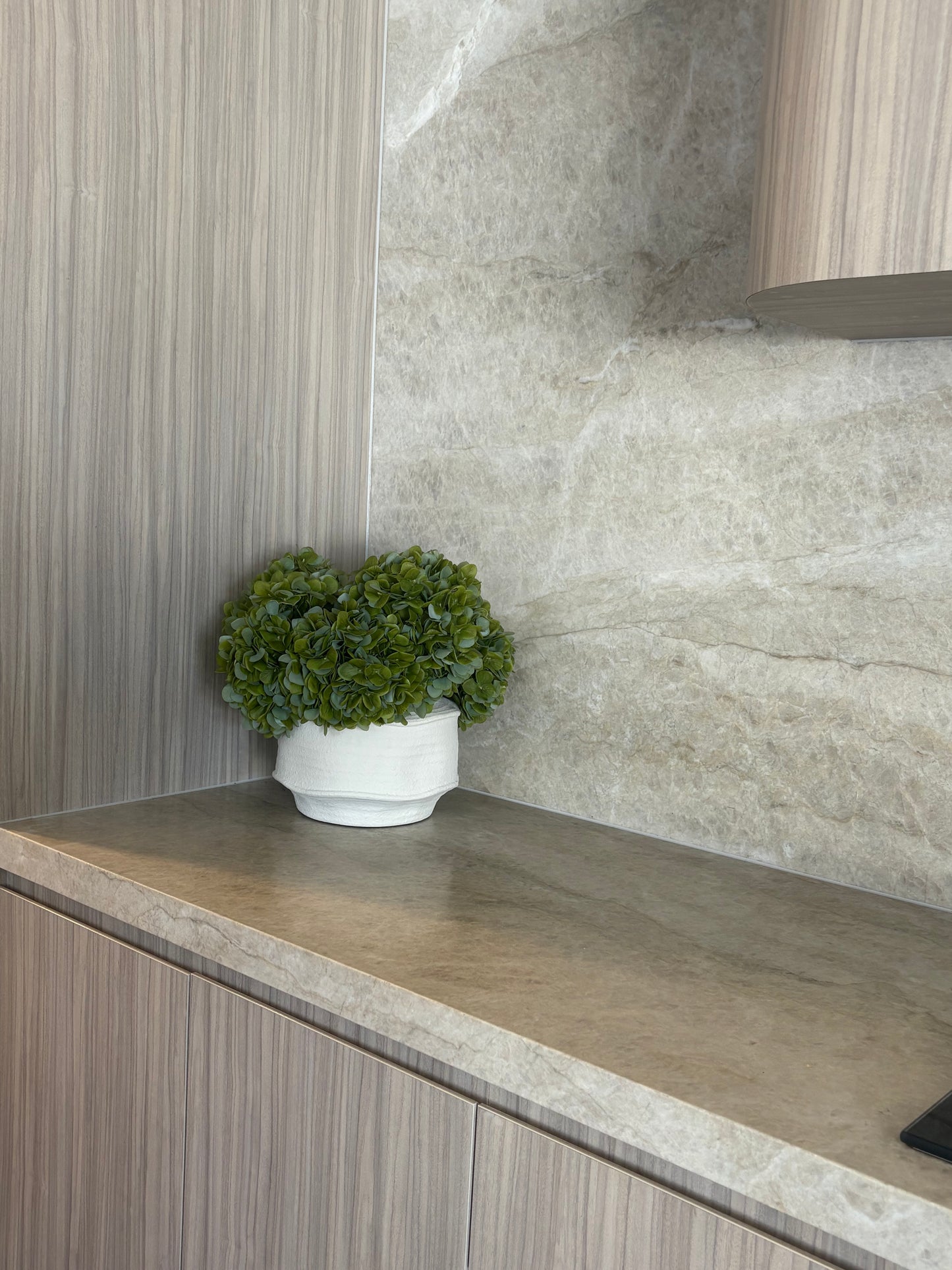 Real-touch green hydrangea arrangement in textured white pot placed in beige modern home interior