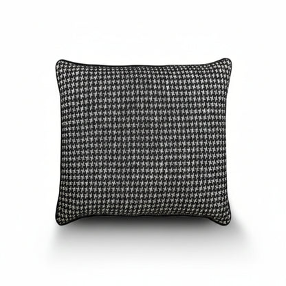 A square throw pillow featuring a classic black and white houndstooth pattern, finished with a solid black piped edge, shown against a plain white background with a soft drop shadow.