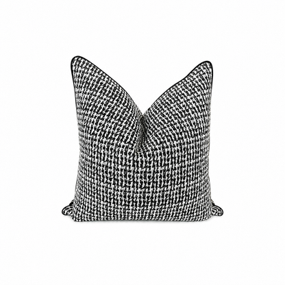 A square throw pillow featuring a black and white houndstooth pattern with black piping along the edges, shown against a plain white background.